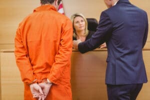 Lawyer and judge speaking next to the criminal in handcuffs