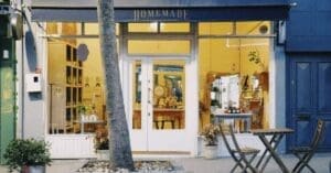 downloaded-image - Local SEO and Search Engine Marketing | FMS Online Marketing Storefront with white double doors, warm yellow interior, and outdoor table and chairs; sign above reads 'Homemade Aromatherapy' in blue.