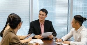 downloaded-image - Local SEO and Search Engine Marketing | FMS Online Marketing Group of four professionals in a meeting around a wooden table, discussing documents and notes.