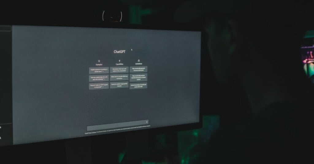 Dimly lit room with a computer monitor showing the ChatGPT interface on screen.