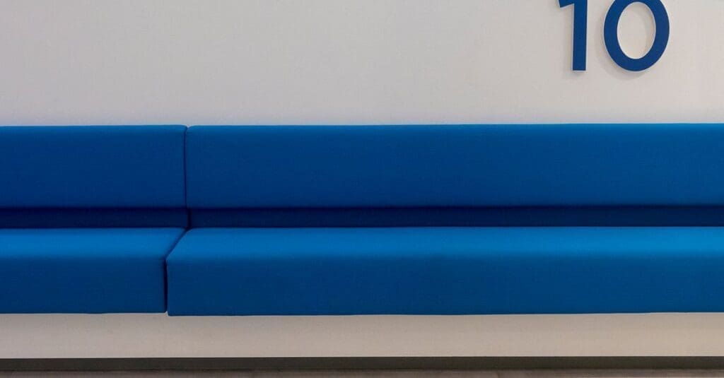 Blue cushioned bench seating along a white wall with the number 10 visible on the wall.