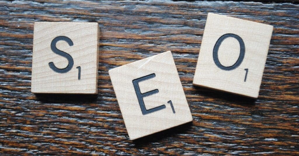 Wooden Scrabble tiles spell SEO on a dark wood surface.
