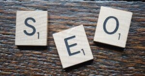 Wooden Scrabble tiles spell SEO on a dark wood surface.